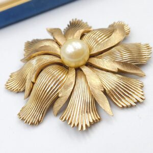 Grande e spettacolare spilla Trifari anni '50, realizzata in lega Trifanium color oro con lavorazione a bacchette e satinata, perla solitaria centrale - VINTAGE AMORE MIO