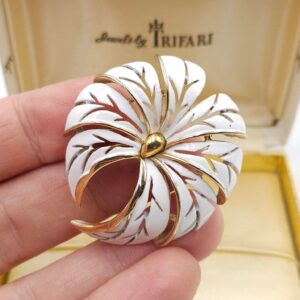 Spilla firmata Trifari risalente alla seconda metà degli anni '50, dalla forma bombata, realizzata in lega Trifanium color oro con smalto bianco - VINTAGE AMORE MIO