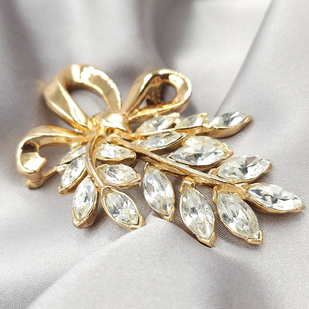Spilla Trifari, risalente ai primi anni '50, realizzata in lega Trifanium color oro con cristalli diamante taglio navette, decoro con fiocco - VINTAGE AMORE MIO