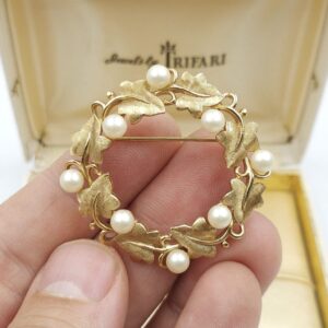Spilla realizzata da Trifari intorno al 1960, a forma di ghirlanda, con squisite foglioline in lega Trifanium color oro satinato e perle, dettagli in lega Trifanium color oro lucido - VINTAGE AMORE MIO