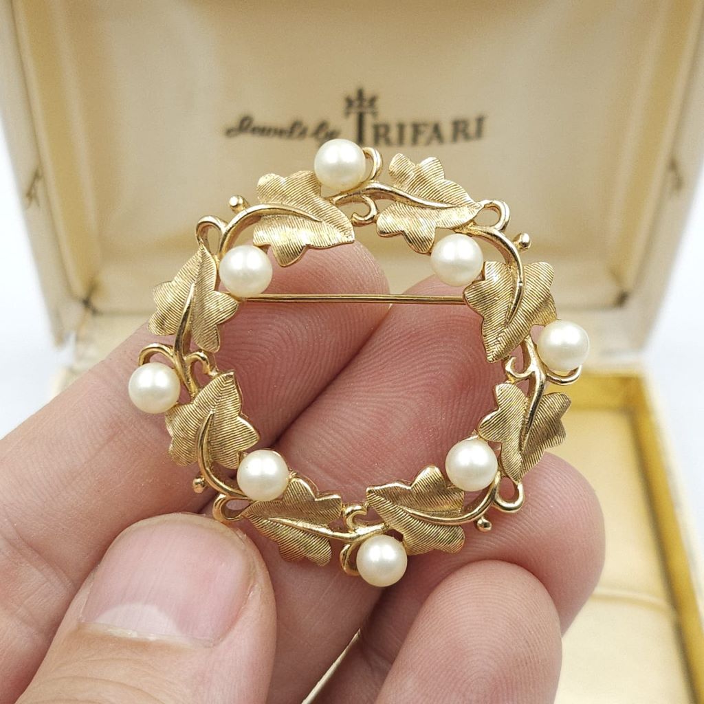 Spilla realizzata da Trifari intorno al 1960, a forma di ghirlanda, con squisite foglioline in lega Trifanium color oro satinato e perle, dettagli in lega Trifanium color oro lucido - VINTAGE AMORE MIO