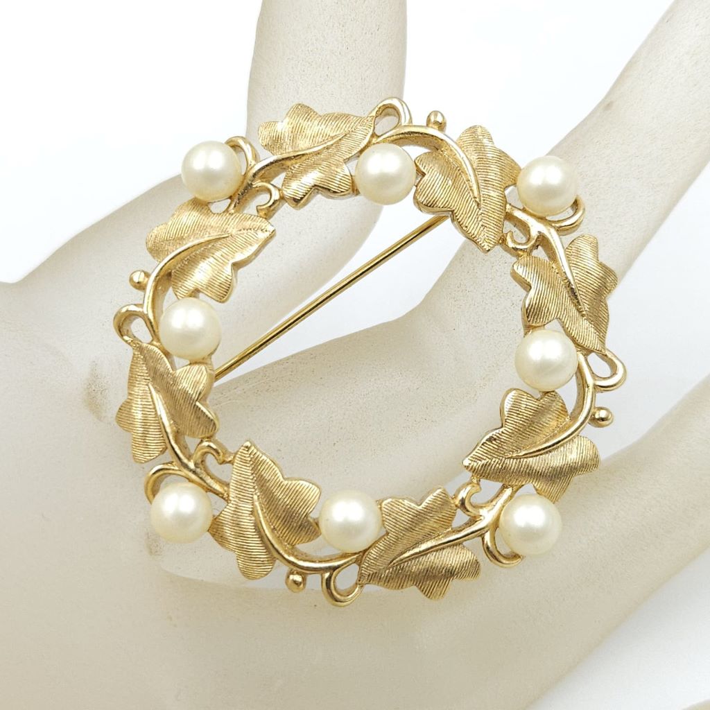 Spilla realizzata da Trifari intorno al 1960, a forma di ghirlanda, con squisite foglioline in lega Trifanium color oro satinato e perle, dettagli in lega Trifanium color oro lucido - VINTAGE AMORE MIO
