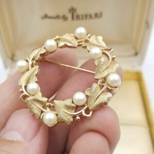 Spilla realizzata da Trifari intorno al 1960, a forma di ghirlanda, con squisite foglioline in lega Trifanium color oro satinato e perle, dettagli in lega Trifanium color oro lucido - VINTAGE AMORE MIO