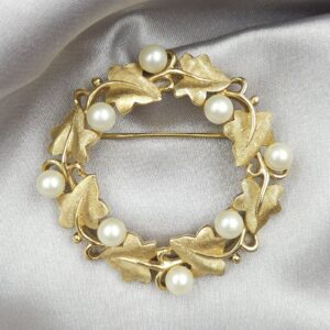 Spilla realizzata da Trifari intorno al 1960, a forma di ghirlanda, con squisite foglioline in lega Trifanium color oro satinato e perle, dettagli in lega Trifanium color oro lucido - VINTAGE AMORE MIO