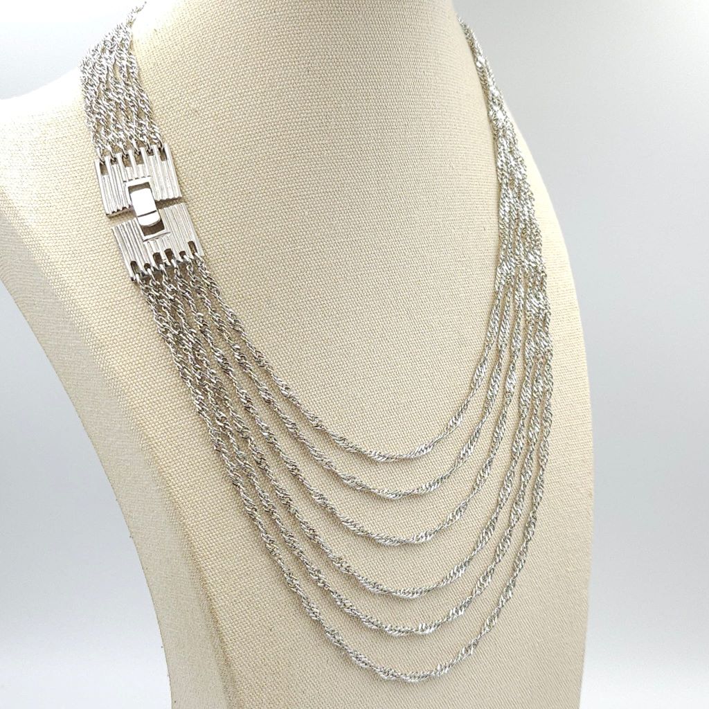 Collana firmata Trifari risalente alla seconda metà degli anni '50, realizzata in lega Trifanium color argento, con sei catene a torchon di lunghezza gradata e chiusura di ispirazione decò - VINTAGE AMORE MIO Collana firmata Trifari risalente alla seconda metà degli anni '50, realizzata in lega Trifanium color argento, con sei catene a torchon di lunghezza gradata e chiusura di ispirazione decò - VINTAGE AMORE MIO