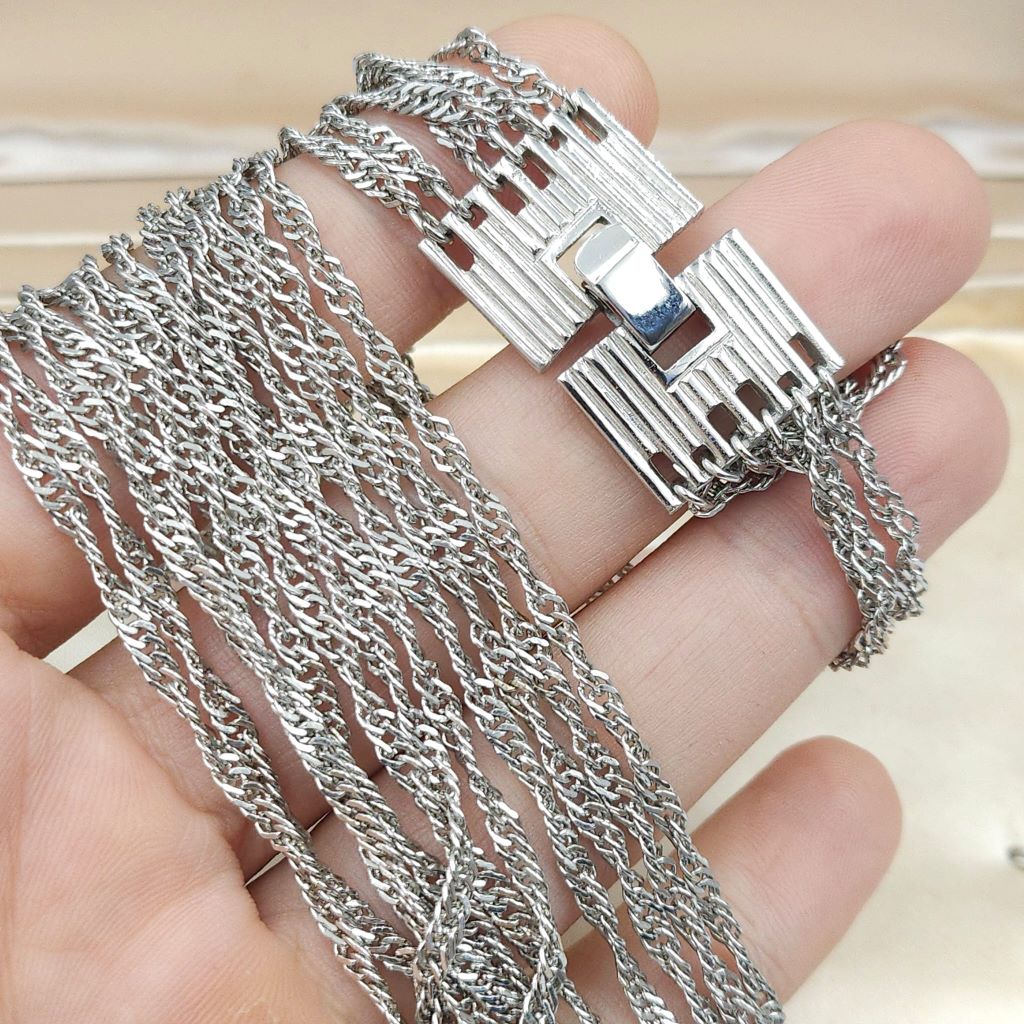 Collana firmata Trifari risalente alla seconda metà degli anni '50, realizzata in lega Trifanium color argento, con sei catene a torchon di lunghezza gradata e chiusura di ispirazione decò - VINTAGE AMORE MIO Collana firmata Trifari risalente alla seconda metà degli anni '50, realizzata in lega Trifanium color argento, con sei catene a torchon di lunghezza gradata e chiusura di ispirazione decò - VINTAGE AMORE MIO