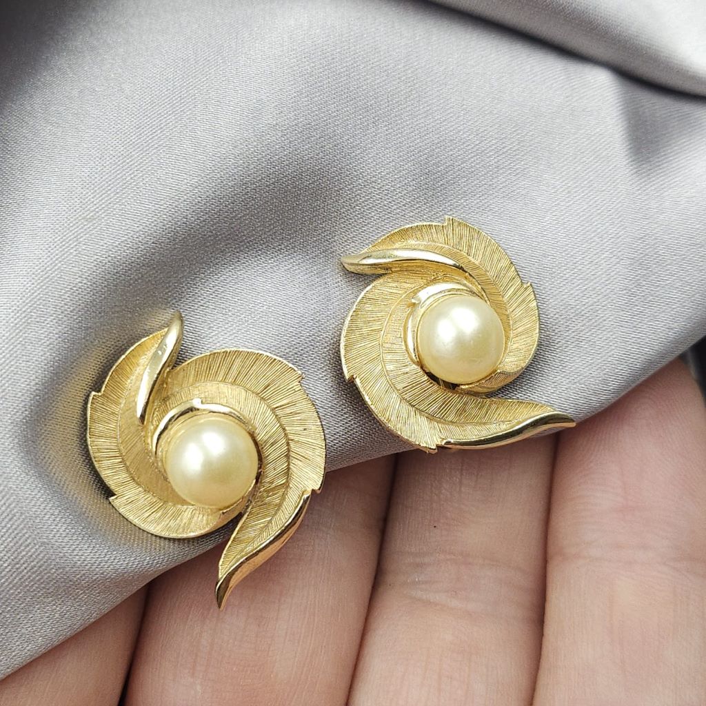 Orecchini a clip Trifari risalenti al 1960 circa, realizzati in lega Trifanium color oro satinato con piccoli dettagli lucidi con perla centrale - VINTAGE AMORE MIO Orecchini a clip Trifari risalenti al 1960 circa, realizzati in lega Trifanium color oro satinato con piccoli dettagli lucidi con perla centrale - VINTAGE AMORE MIO