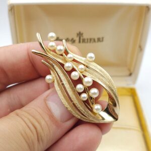 Spilla firmata Trifari risalente alla seconda metà degli anni cinquanta, realizzata in lega Trifanium color oro satinato con dettagli lucidi e perle - VINTAGE AMORE MIO Spilla firmata Trifari risalente alla seconda metà degli anni cinquanta, realizzata in lega Trifanium color oro satinato con dettagli lucidi e perle - VINTAGE AMORE MIO