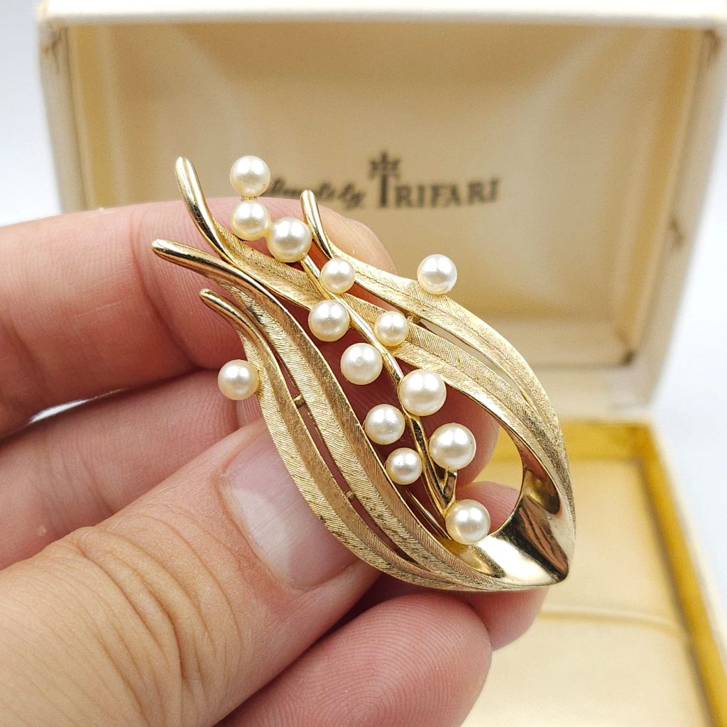 Spilla firmata Trifari risalente alla seconda metà degli anni cinquanta, realizzata in lega Trifanium color oro satinato con dettagli lucidi e perle - VINTAGE AMORE MIO Spilla firmata Trifari risalente alla seconda metà degli anni cinquanta, realizzata in lega Trifanium color oro satinato con dettagli lucidi e perle - VINTAGE AMORE MIO