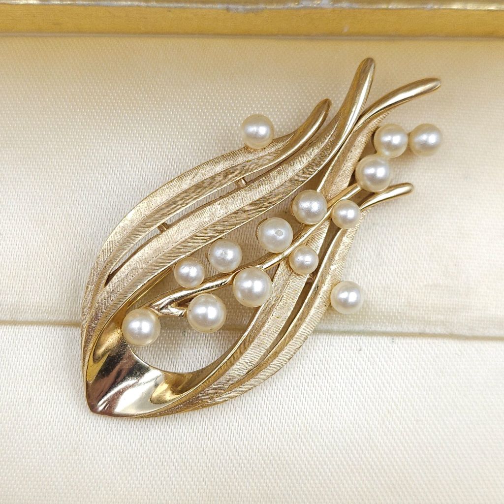 Spilla firmata Trifari risalente alla seconda metà degli anni cinquanta, realizzata in lega Trifanium color oro satinato con dettagli lucidi e perle - VINTAGE AMORE MIO Spilla firmata Trifari risalente alla seconda metà degli anni cinquanta, realizzata in lega Trifanium color oro satinato con dettagli lucidi e perle - VINTAGE AMORE MIO
