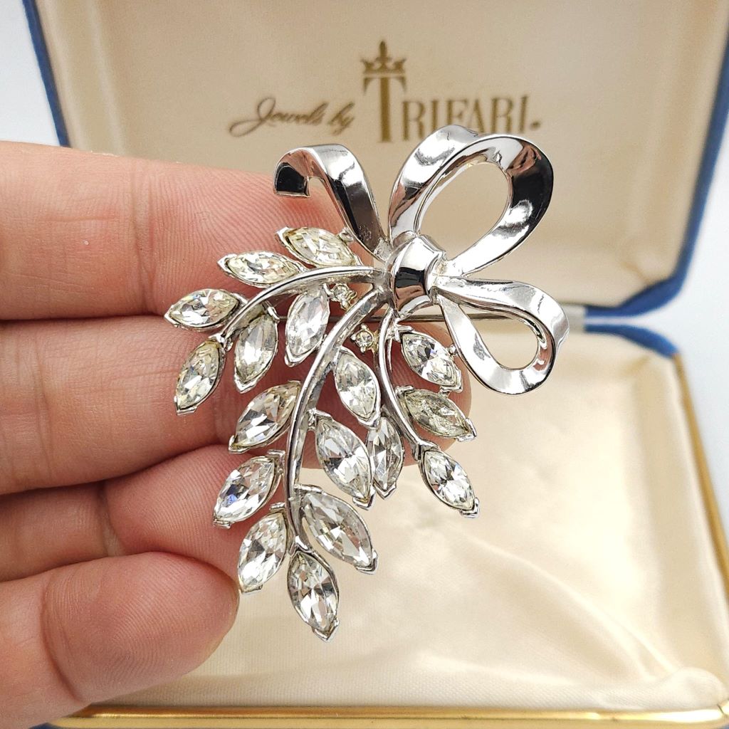 Spilla Trifari anni '50 a forma di raffinato fiocco in lega Trifanium color platino, con cristalli diamante taglio navette - VINTAGE AMORE MIO Spilla Trifari anni '50 a forma di raffinato fiocco in lega Trifanium color platino, con cristalli diamante taglio navette - VINTAGE AMORE MIO