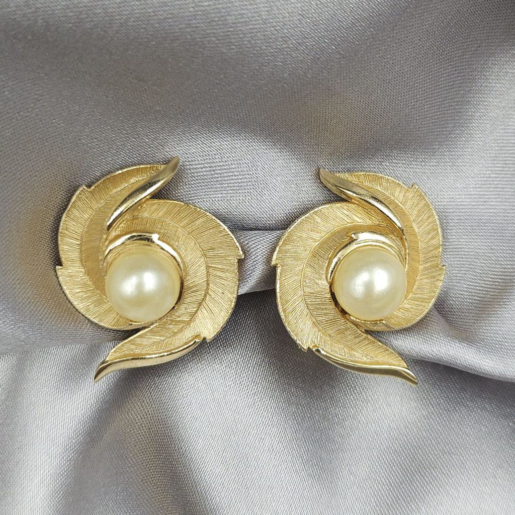 Orecchini a clip Trifari risalenti al 1960 circa, realizzati in lega Trifanium color oro satinato con piccoli dettagli lucidi con perla centrale - VINTAGE AMORE MIO Orecchini a clip Trifari risalenti al 1960 circa, realizzati in lega Trifanium color oro satinato con piccoli dettagli lucidi con perla centrale - VINTAGE AMORE MIO