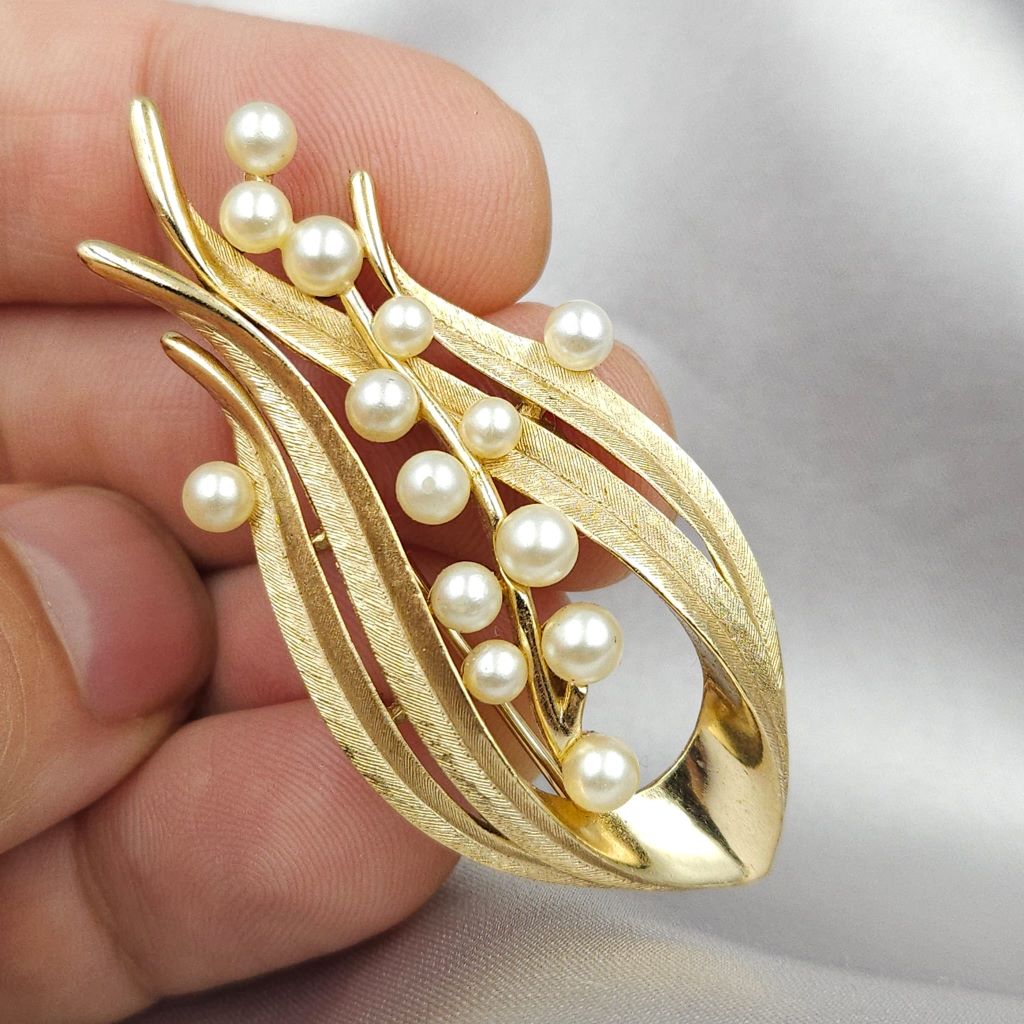 Spilla firmata Trifari risalente alla seconda metà degli anni cinquanta, realizzata in lega Trifanium color oro satinato con dettagli lucidi e perle - VINTAGE AMORE MIO Spilla firmata Trifari risalente alla seconda metà degli anni cinquanta, realizzata in lega Trifanium color oro satinato con dettagli lucidi e perle - VINTAGE AMORE MIO