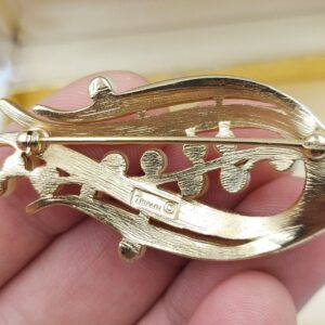 Spilla firmata Trifari risalente alla seconda metà degli anni cinquanta, realizzata in lega Trifanium color oro satinato con dettagli lucidi e perle - VINTAGE AMORE MIO Spilla firmata Trifari risalente alla seconda metà degli anni cinquanta, realizzata in lega Trifanium color oro satinato con dettagli lucidi e perle - VINTAGE AMORE MIO