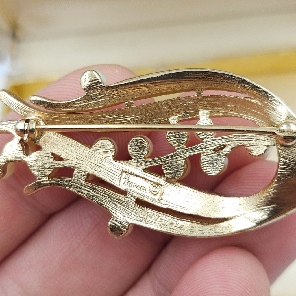 Spilla firmata Trifari risalente alla seconda metà degli anni cinquanta, realizzata in lega Trifanium color oro satinato con dettagli lucidi e perle - VINTAGE AMORE MIO Spilla firmata Trifari risalente alla seconda metà degli anni cinquanta, realizzata in lega Trifanium color oro satinato con dettagli lucidi e perle - VINTAGE AMORE MIO